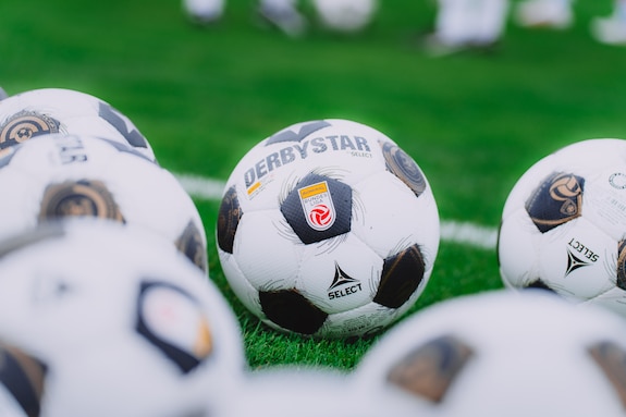 Fußbälle der österreichischen Bundesliga liegen auf grünem Rasen