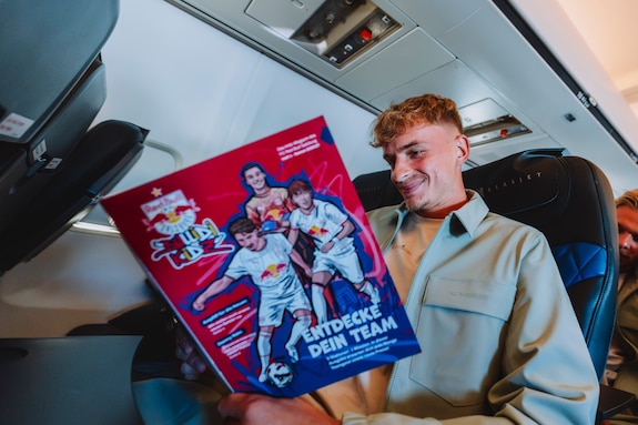 Fußballer Oscar Gloukh liest Magazin im Flugzeug auf dem Weg nach Salzburg.