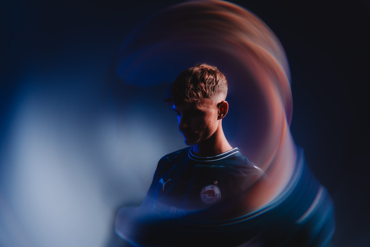 Fußballspieler des FC Salzburg im Trikot mit Lichteffekten vor dunklem Hintergrund.