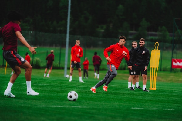 Fußballer im Training auf Kunstrasen, Spieler in roten Trikots laufen