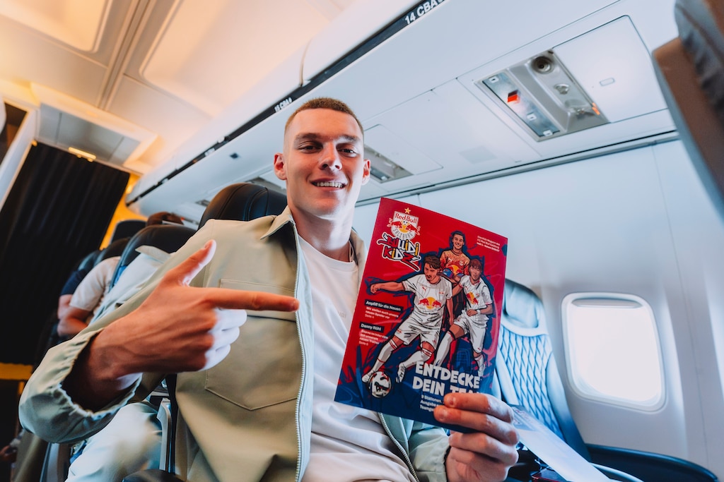 Karim Konaté hält ein Red Bull Kids Magazin im Flugzeug in Salzburg.