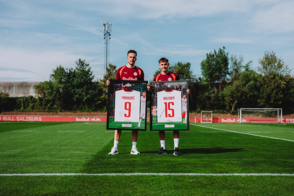 Fußballer Tabakovic und Mazurek halten gerahmte Trikots im Stadion von RB Salzburg.