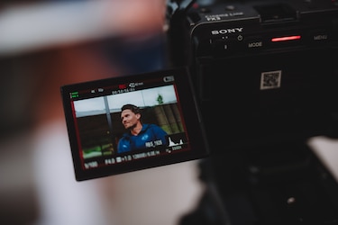 Sony-Kamera zeigt Mann im blauen Trikot vor grünem Zaun.