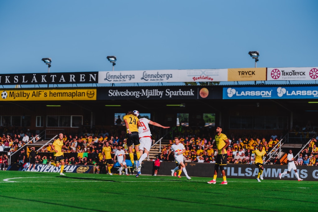 Fußballspiel: Spieler im Sprung zum Kopfball vor Zuschauern im Stadion in Schweden