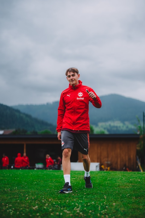 Fußballer Noah Katterbach im Trainingsanzug von Red Bull Salzburg auf einem grünen Rasen.
