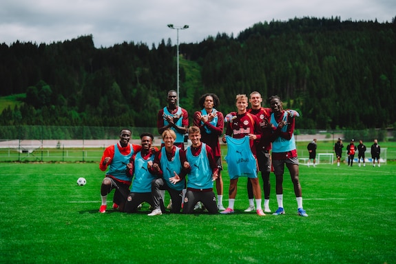 Fußball-Mannschaft mit Trainingsleibchen und Trikots auf einem Rasen in den österreichischen Alpen