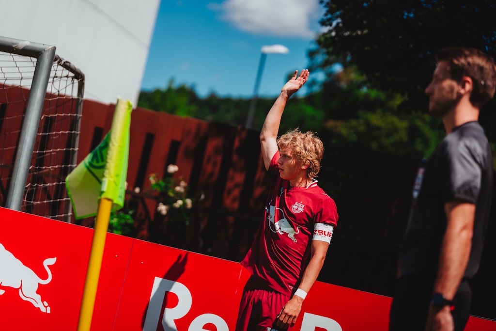 Fußballspieler mit hochgereckter Hand und Trainer in Salzburg.