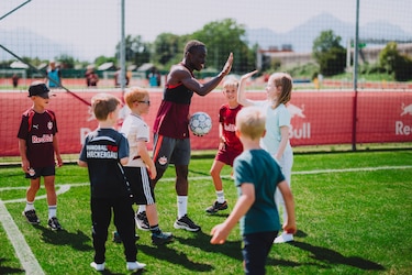 Fußballer Sekou Koita gibt Kindern auf einem Trainingsplatz in Salzburg einen High-Five.