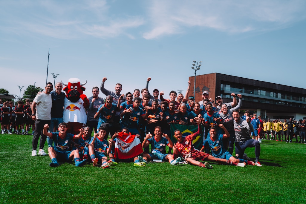 Fußballteam mit Maskottchen und Betreuern feiert auf einem Rasenplatz in Österreich.